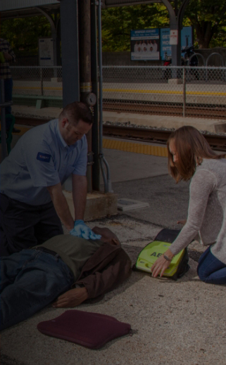 Image of two individuals using an AED and performing CPR on an incapacitated individual.