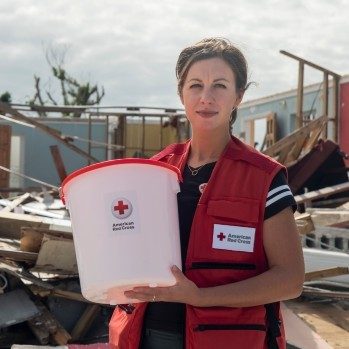 Red Cross volunteer holding bucket with American Red Cross logo