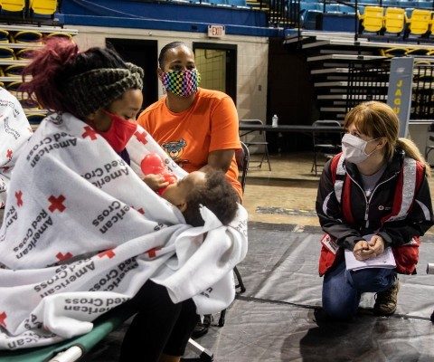 A Red Cross volunteer talks with a family staying in an emergency shelter.