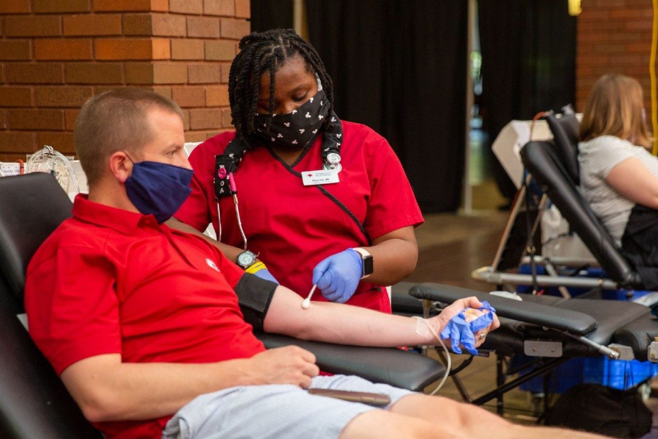 A Red Cross phlebotomist prepares a blood donor for his donation